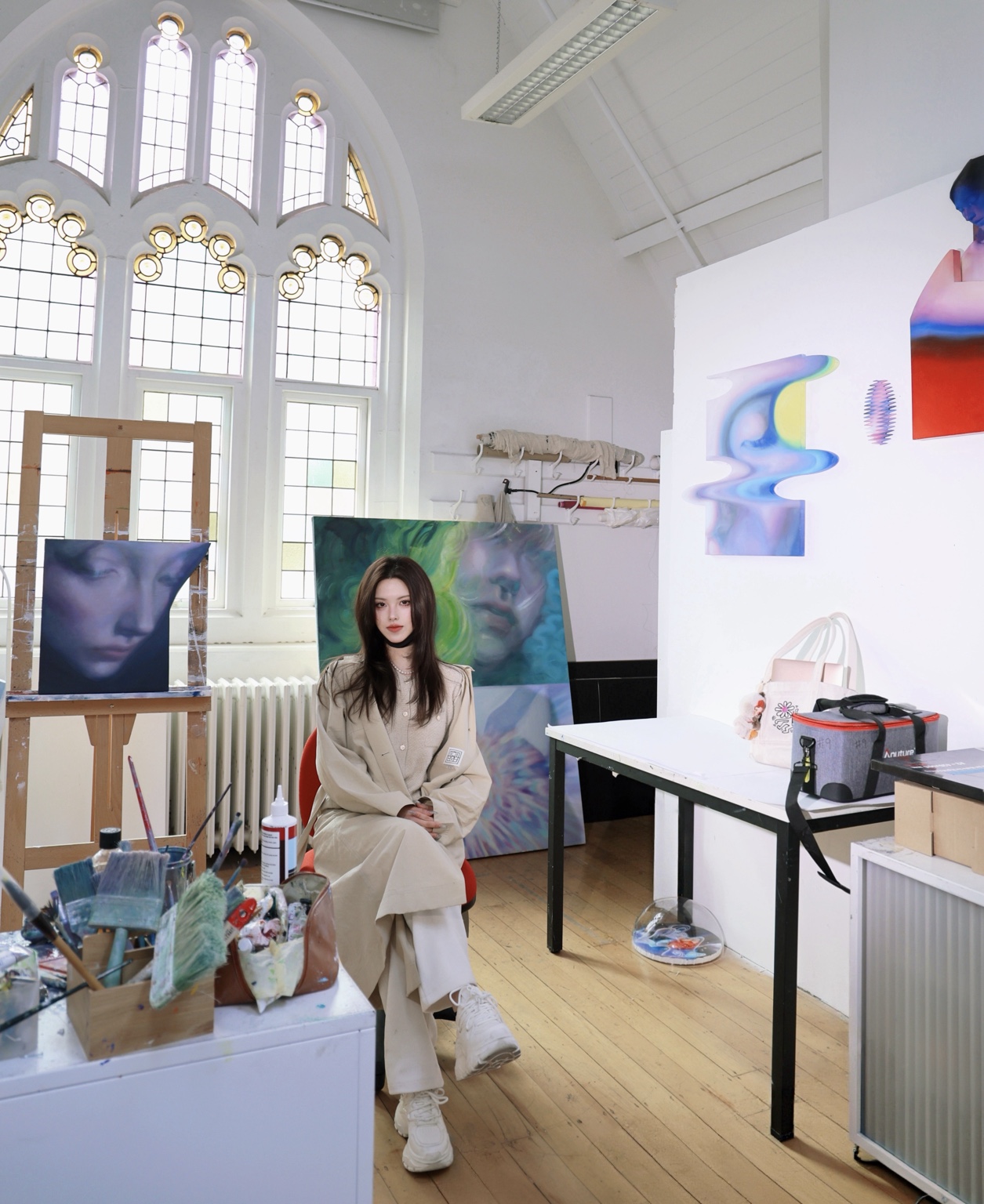 Anna Xiang seated in her painting studio with artworks